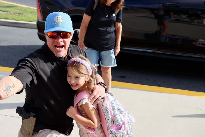 Mark Nicholas, school constable, was giving out a lot of hugs, including one to Hope Coulter, who was arriving for her first day of school. BILL SHULL PHOTO